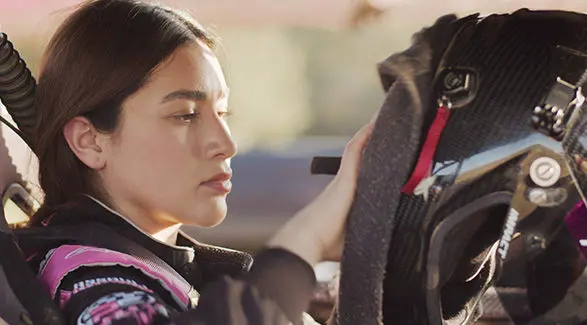 Fernanda Montiel inside her Polaris RZR SxS, putting on her helmet and preparing for a race.