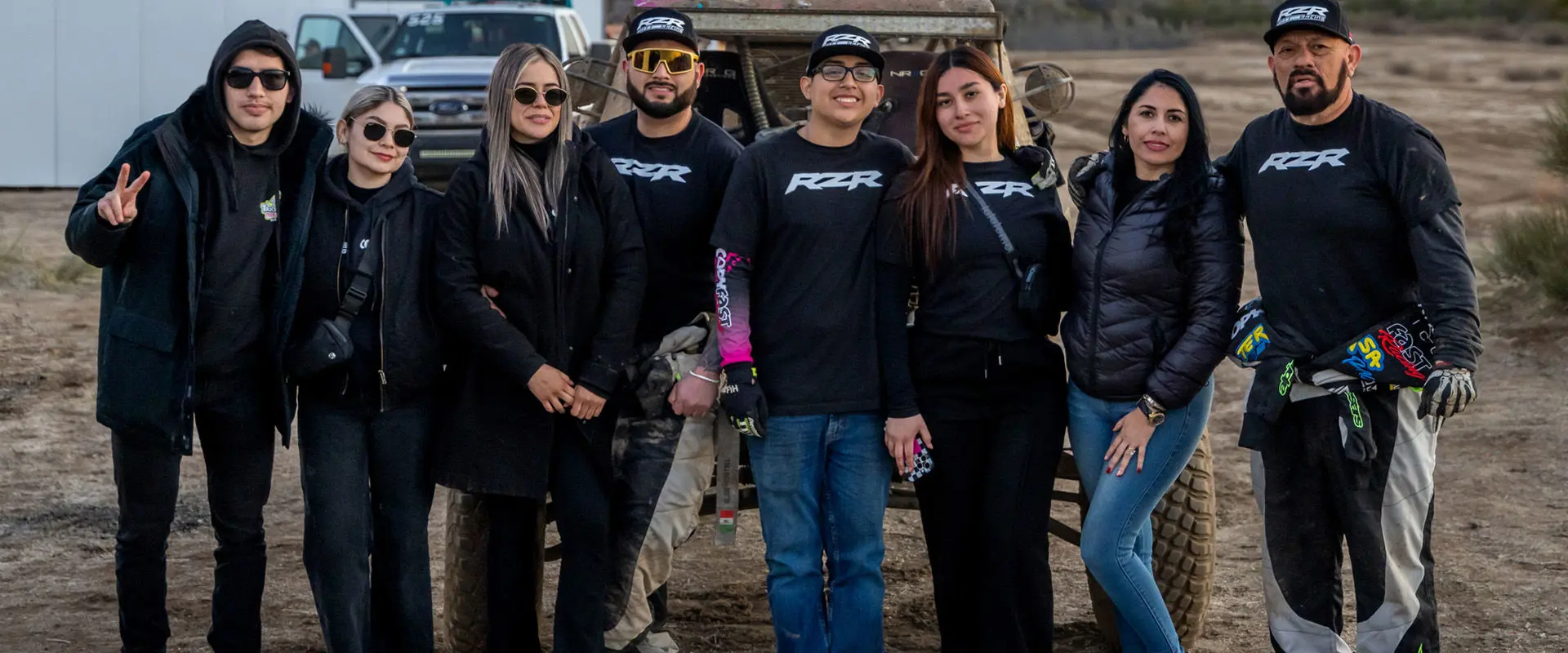 Fernanda Montiel and her friends posing in front of a Polaris RZR SxS at a racing event.