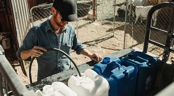 Brent Underwood fills blue and white containers in the cargo bed of a Polaris RANGER XP 1000.