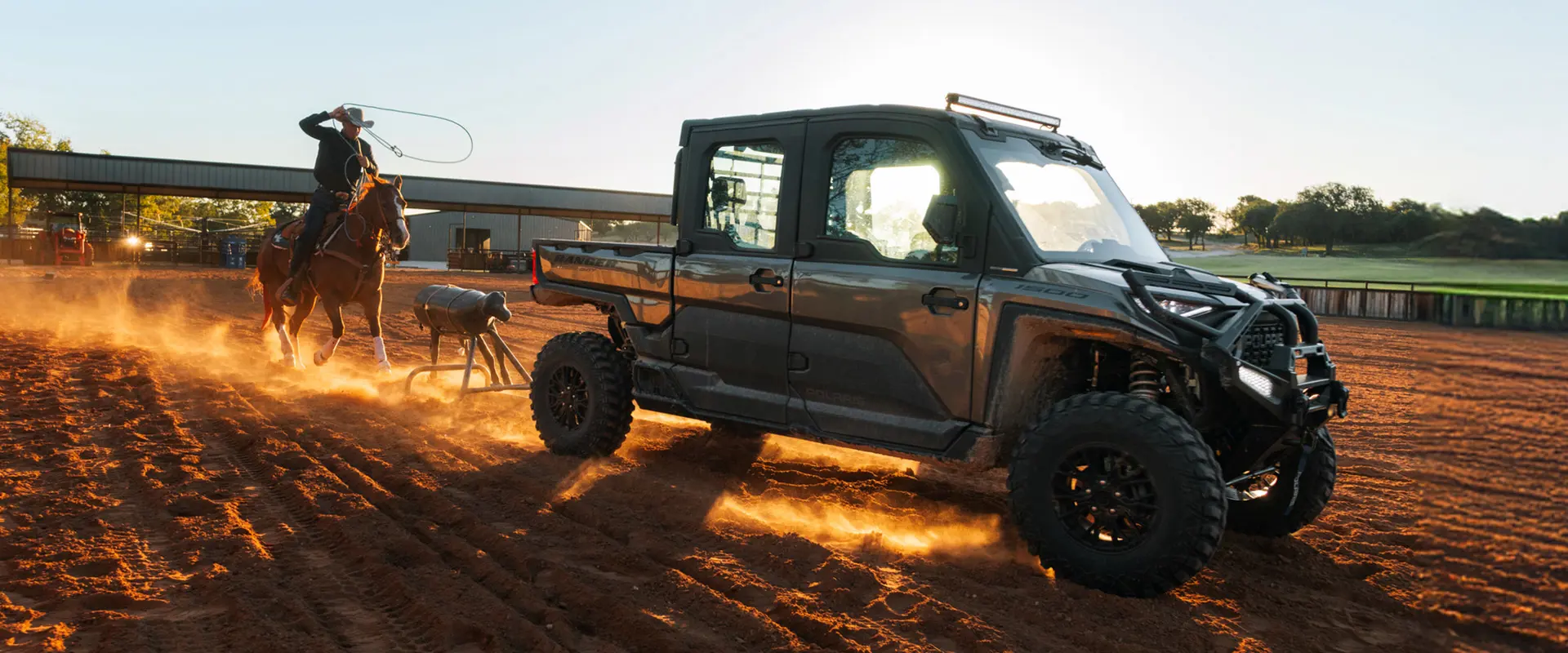 Shad Mayfield on horseback practices roping a dummy calf in a sunlit arena, with a Polaris RANGER XD 1500 NorthStar Edition UTV in the background.