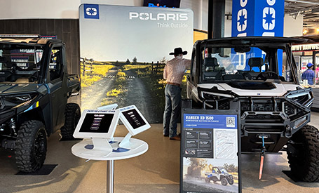 Polaris exhibition booth featuring a white RANGER XD 1500 UTV and a visitor in a cowboy hat exploring the display.