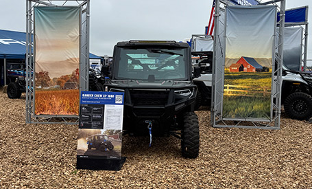 A black Polaris RANGER UTV displayed under a banner reading FARMING DOESN'T STOP FOR THE WEATHER at an outdoor event.