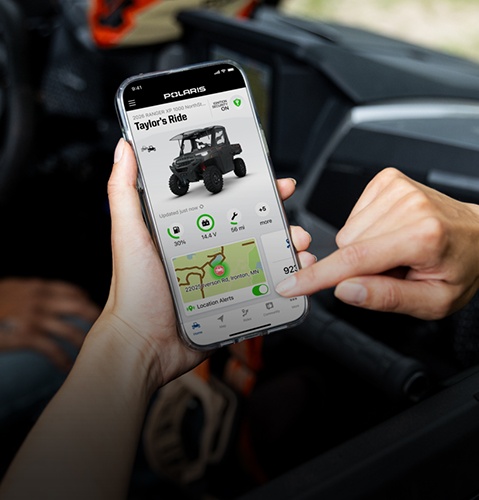 Personne utilisant les fonctions RIDE COMMAND+ de l’application RIDE COMMAND sur un appareil mobile.