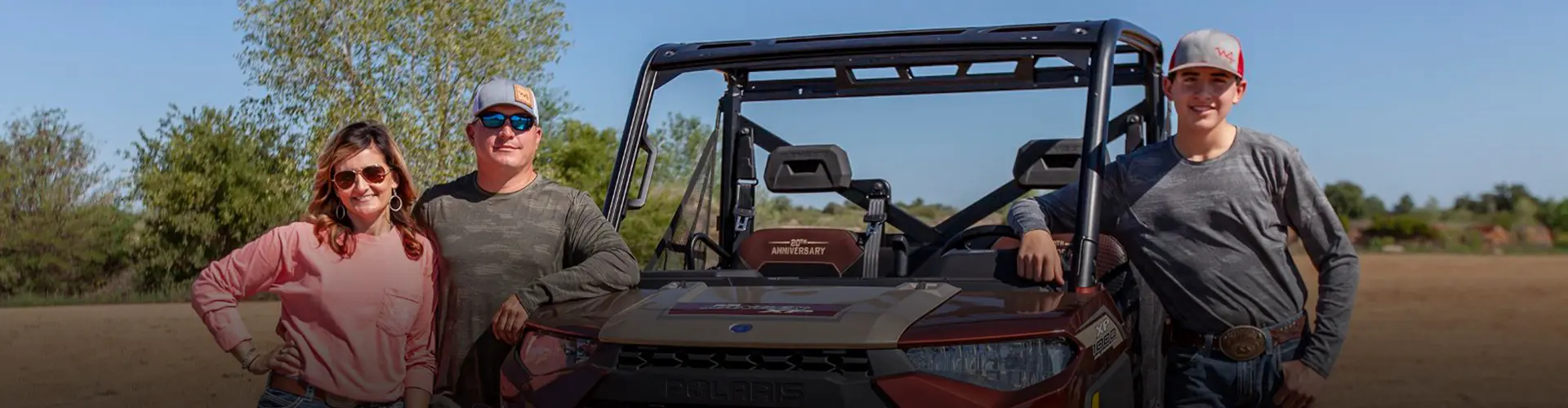 Woodward Family pose beside a Polaris RANGER 20th Anniversary UTV during the Ultimate Rodeo Experience, with an outdoor ranch setting.