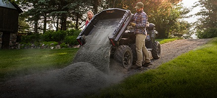 Person dumping rocks out of the versatile cargo box on a 2026 6-wheeled ATV.