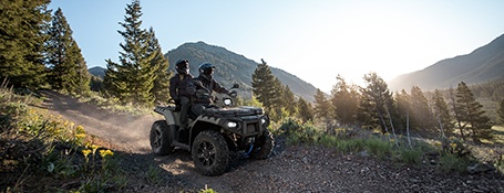 2 riders on a 2-up touring ATV cruising down a rocky trail.