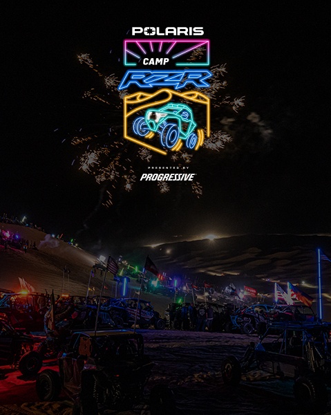 Polaris RZR off-road vehicles and attendees gathered under colorful lights at the Camp RZR nighttime event.