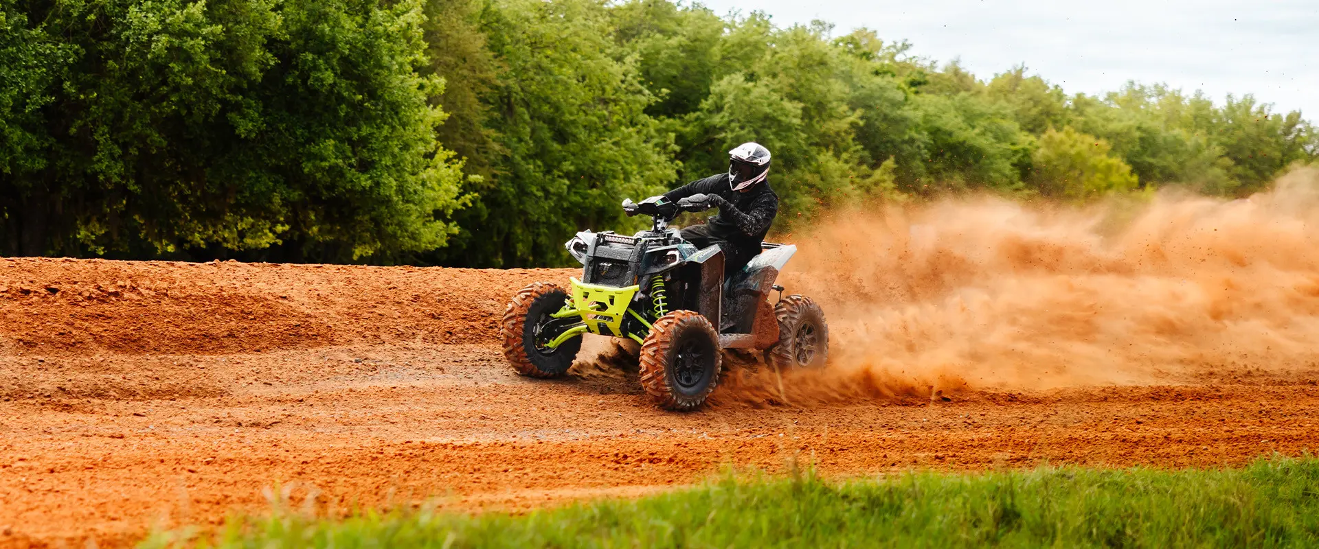 Cleetus McFarland drifts a Polaris Scrambler XP 1000 S ATV with lime green accents on a dirt track at the Freedom Factory.