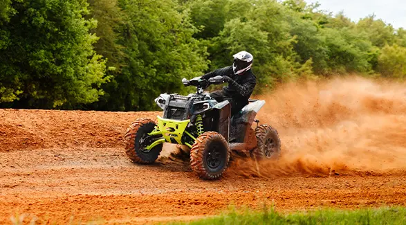 Cleetus McFarland drifts a Polaris Scrambler XP 1000 S ATV with lime green accents on a dirt track at the Freedom Factory.