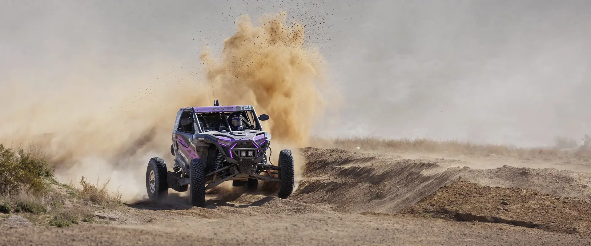 2025 Polaris RZR Pro R Factory side-by-side cornering a dusty trail and throwing sand.