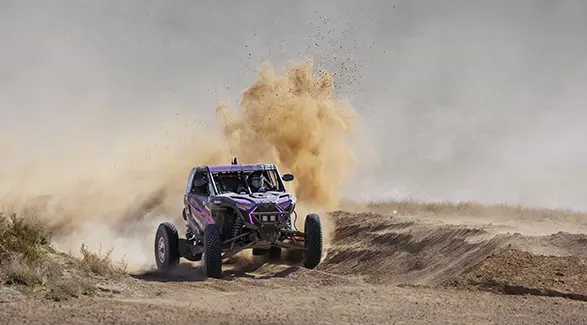 2025 Polaris RZR Pro R Factory side-by-side cornering a dusty trail and throwing sand.