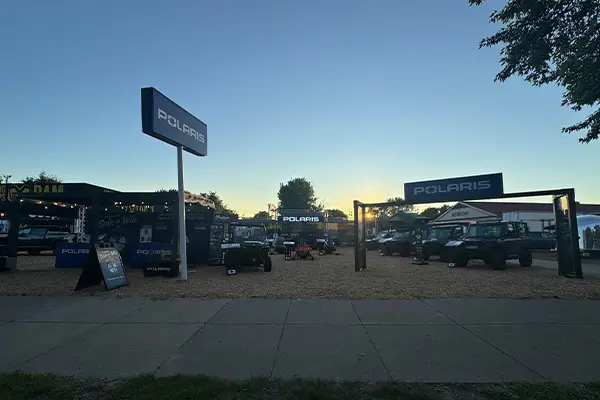 Polaris outdoor event entrance at sunset with multiple Polaris RANGER UTVs and off-road vehicles displayed under branded signs and tents.