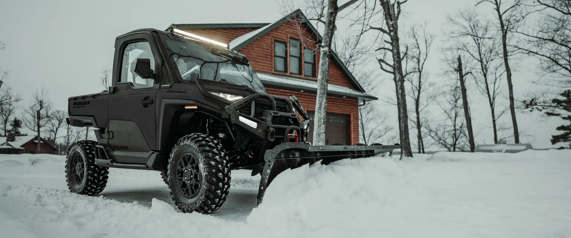 An enclosed cab 3-seater UTV plowing snow in the winter.