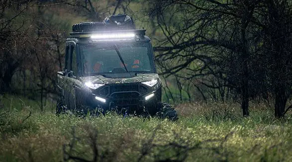 Hunters in a 6-seater enclosed cab UTV driving out to their hunting spots in the rain.