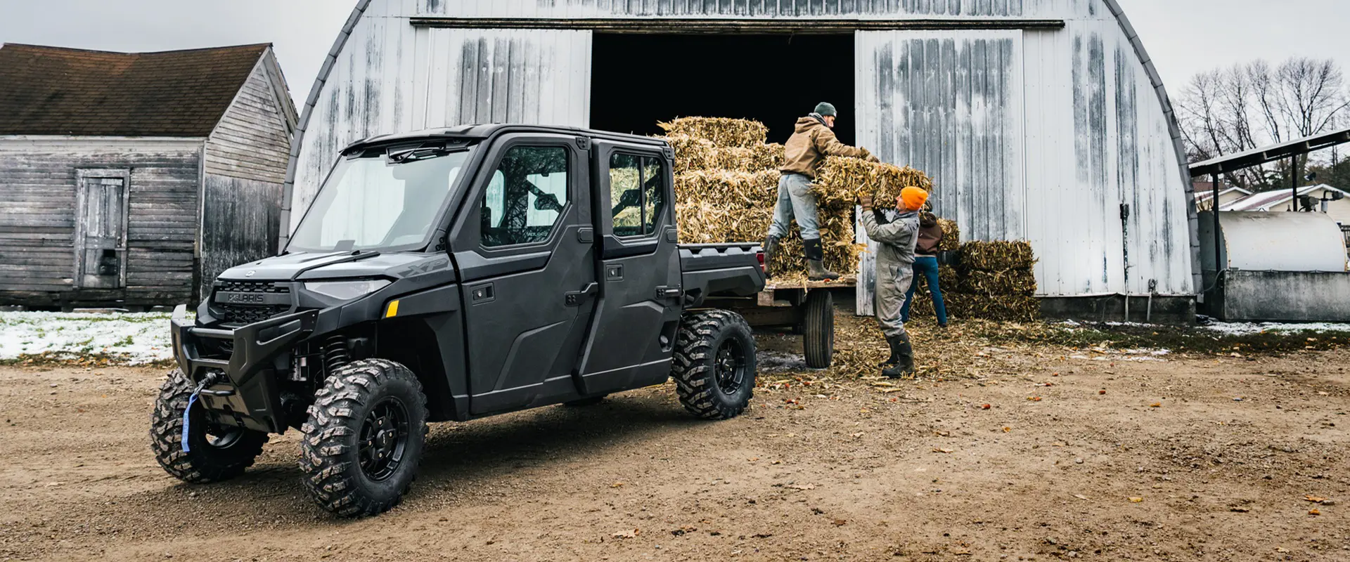 Farmers loading square bales onto a trailer pulled by a 2026 Polaris RANGER CREW XP 1000 NorthStar Edition UTV.
