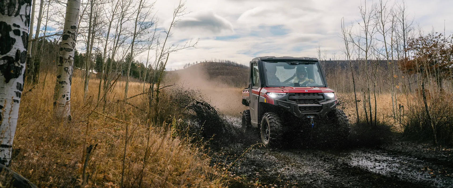 A 2026 Polaris RANGER XP 1000 NorthStar Edition cabbed UTV cruising through a muddy trail.