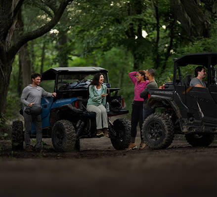 5 people preparing to ride in 2 2026 side-by-sides with cargo boxes.
