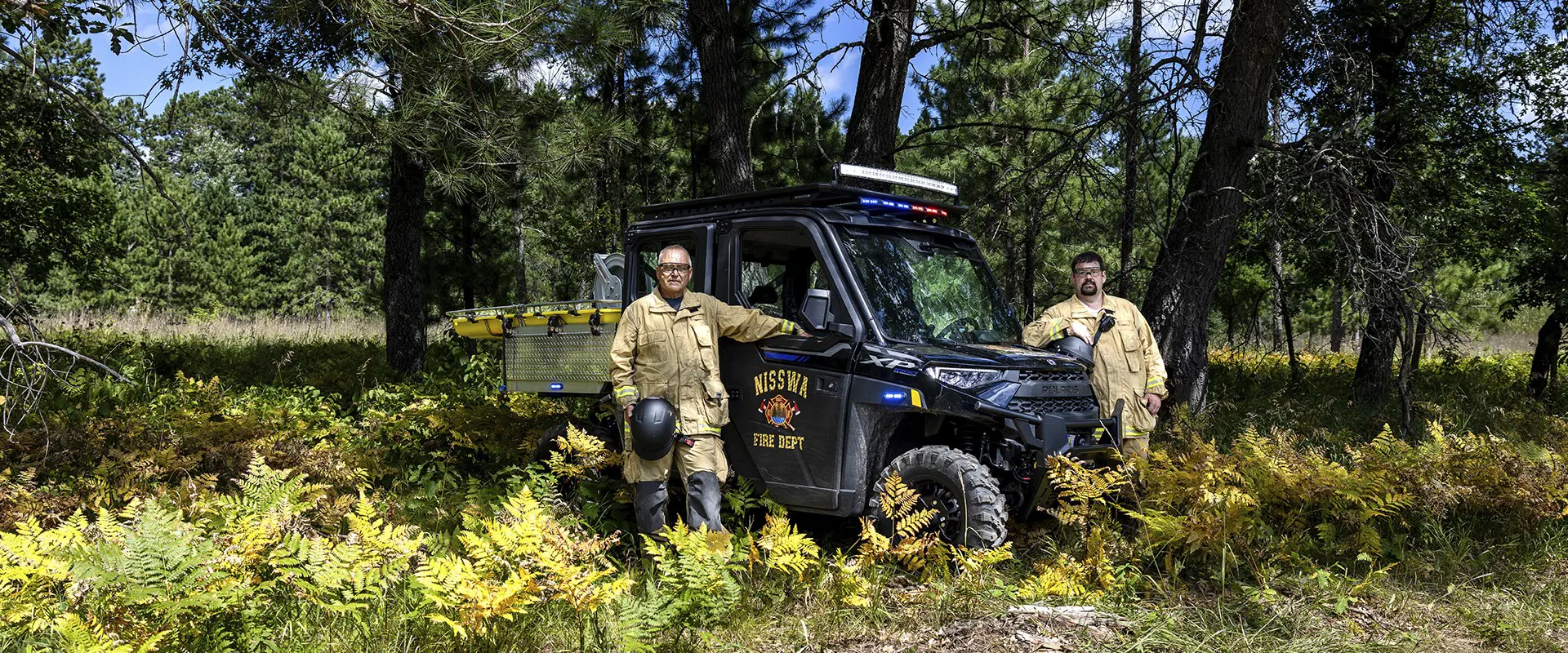 Two Nisswa first responders stand beside a Polaris RANGER rescue side-by-side equipped with emergency lights and a stretcher.