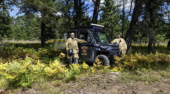 Two Nisswa first responders stand beside a Polaris RANGER rescue side-by-side equipped with emergency lights and a stretcher.