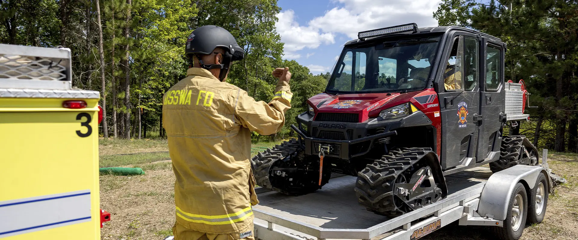 Nisswa first responder guides a tracked Polaris RANGER rescue side-by-side onto a utility trailer.