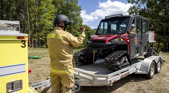 Nisswa first responder guides a tracked Polaris RANGER rescue side-by-side onto a utility trailer.