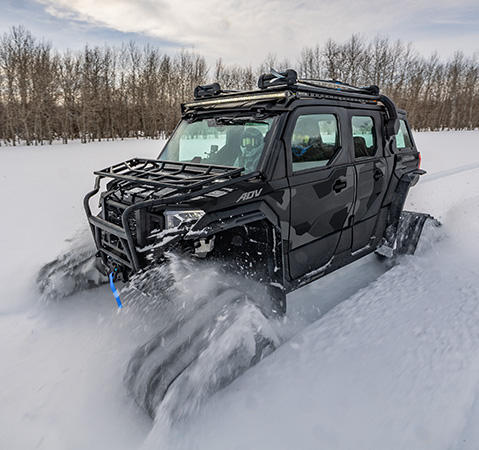 A Polaris XPEDITION ADV 5 NorthStar side-by-side with tracks driving through the snow in the winter.