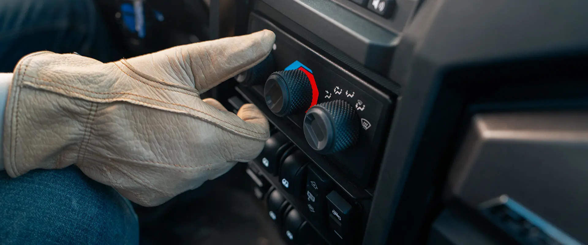 A person turning on the air conditioning in an enclosed cab Polaris NorthStar UTV.