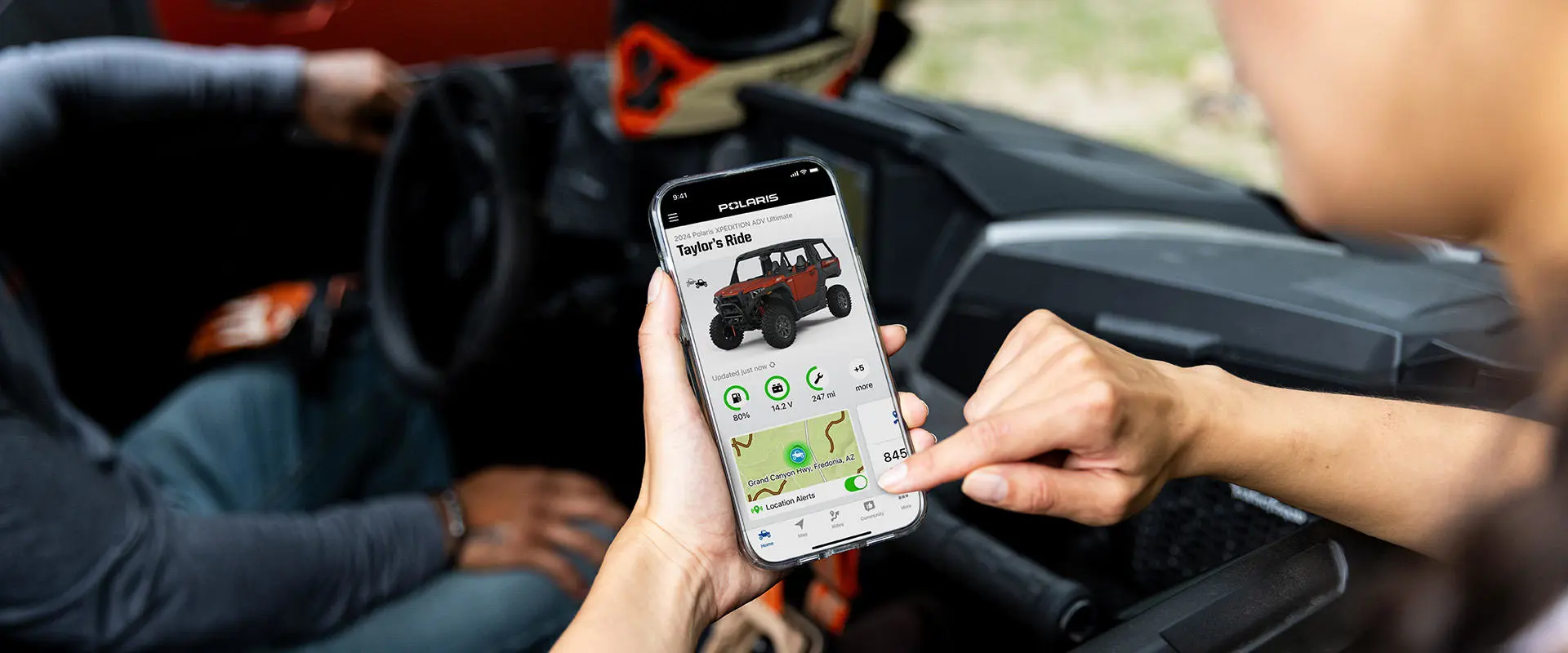 A person using the RIDE COMMAND app on their smartphone to track their Polaris XPEDITION.