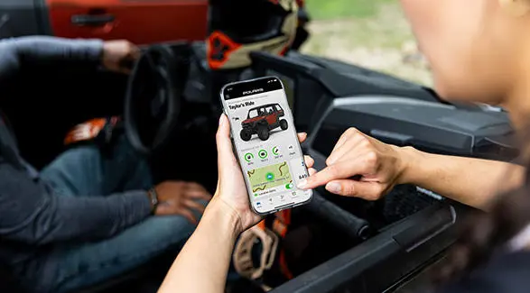 A person using the RIDE COMMAND app on their smartphone to track their Polaris XPEDITION.