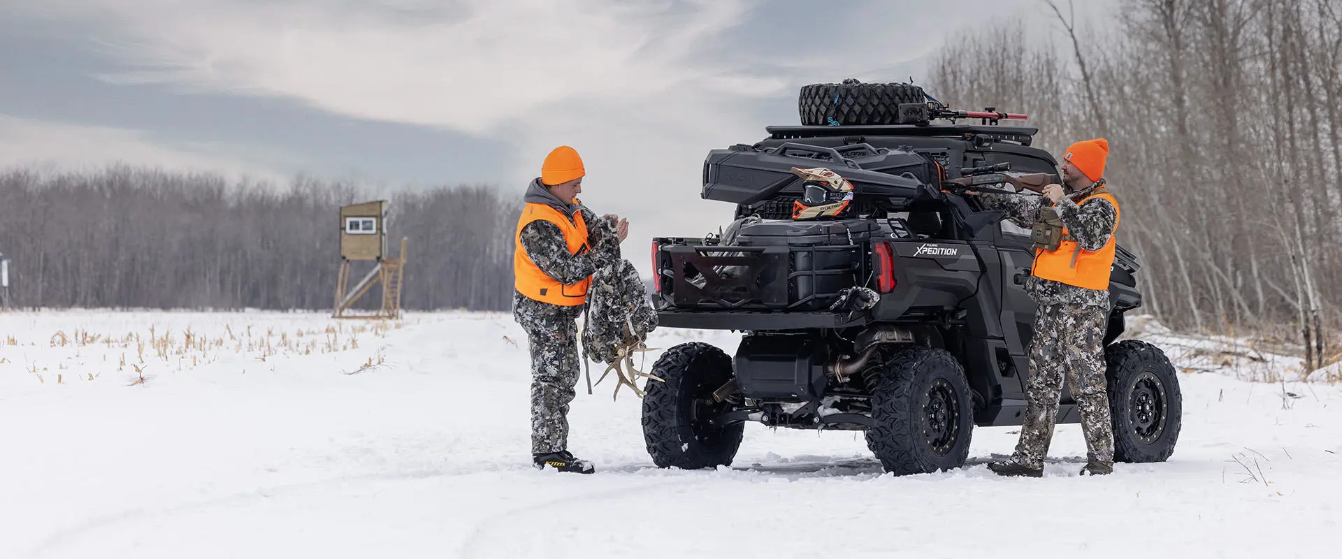 2 hunters unloading gear from their Polaris XPEDITION NorthStar enclosed cab side-by-side.