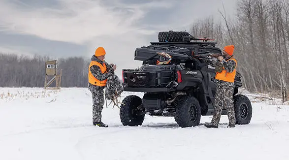 2 hunters unloading gear from their Polaris XPEDITION NorthStar enclosed cab side-by-side.