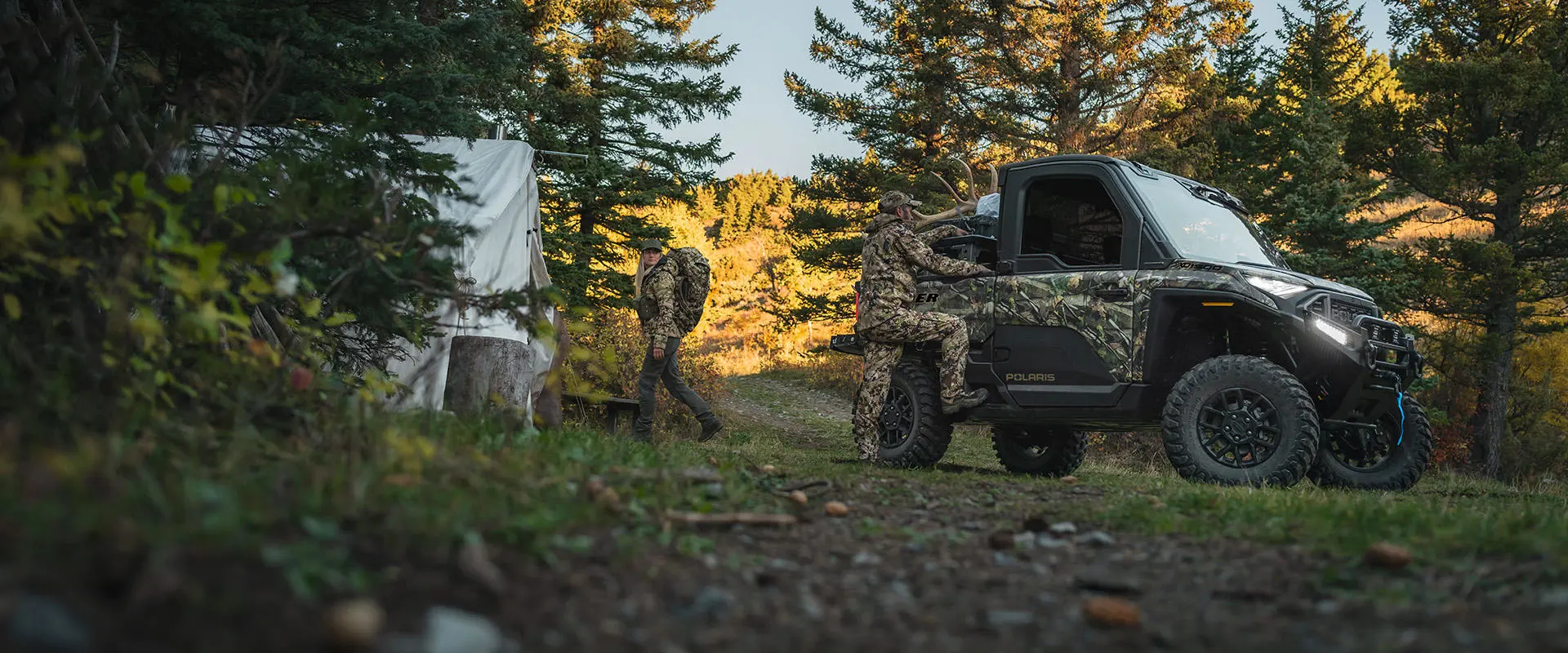 2 hunters grabbing gear from their Polaris RANGER XD 1500 NorthStar enclosed cab UTV at basecamp.