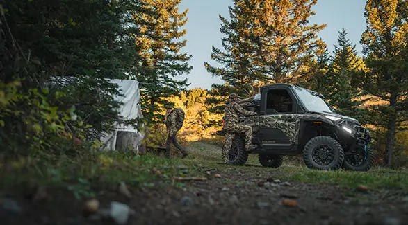 2 hunters grabbing gear from their Polaris RANGER XD 1500 NorthStar enclosed cab UTV at basecamp.