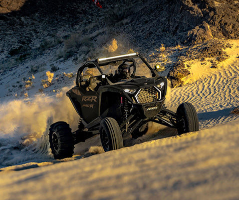 A rugged RZR Pro R side-by-side navigating through the desert, highlighting its durability and performance with the DYNAMIX DV Advance Smart Suspension.