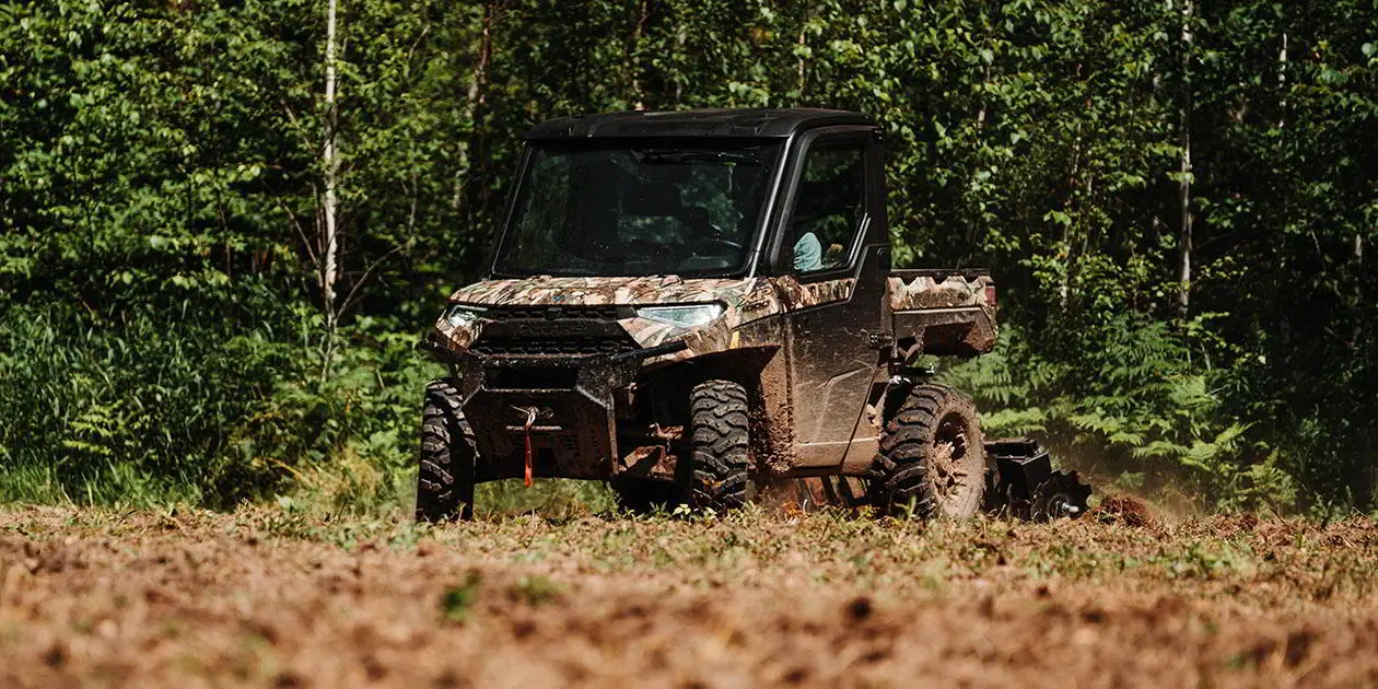 Man riding his Ranger XP 1000 NorthStar Edition vehicle through a food plot