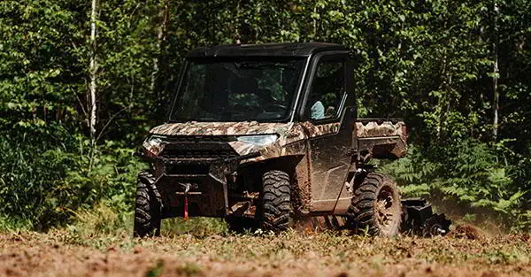 Man riding his Ranger XP 1000 NorthStar Edition vehicle through a food plot