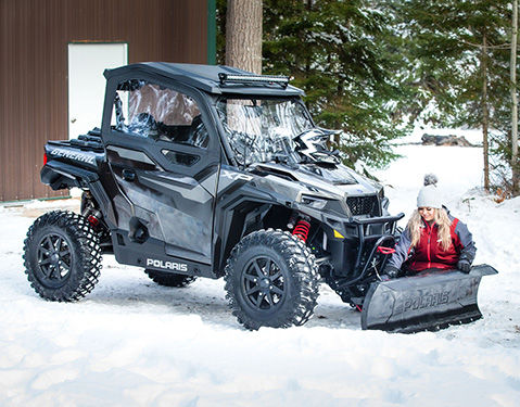 Woman attaches snow plow to a Polaris General Side by Side.