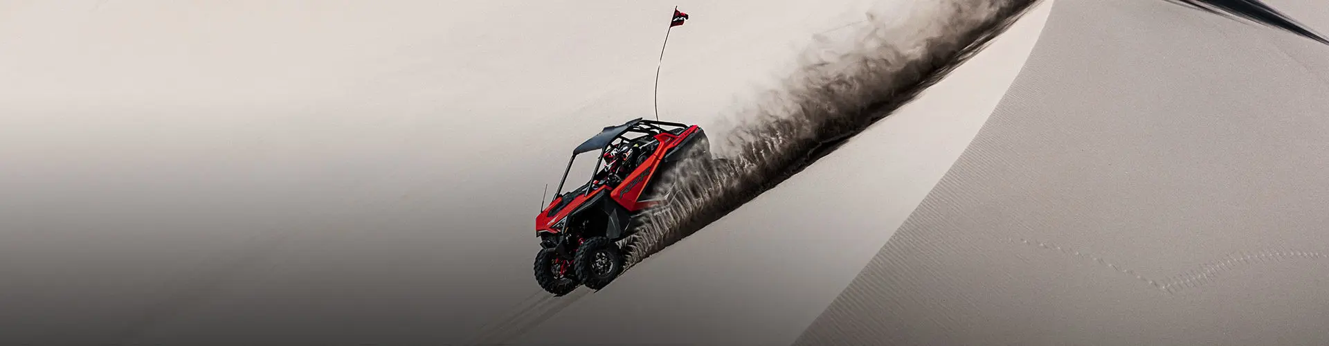 A RZR driven down a dune