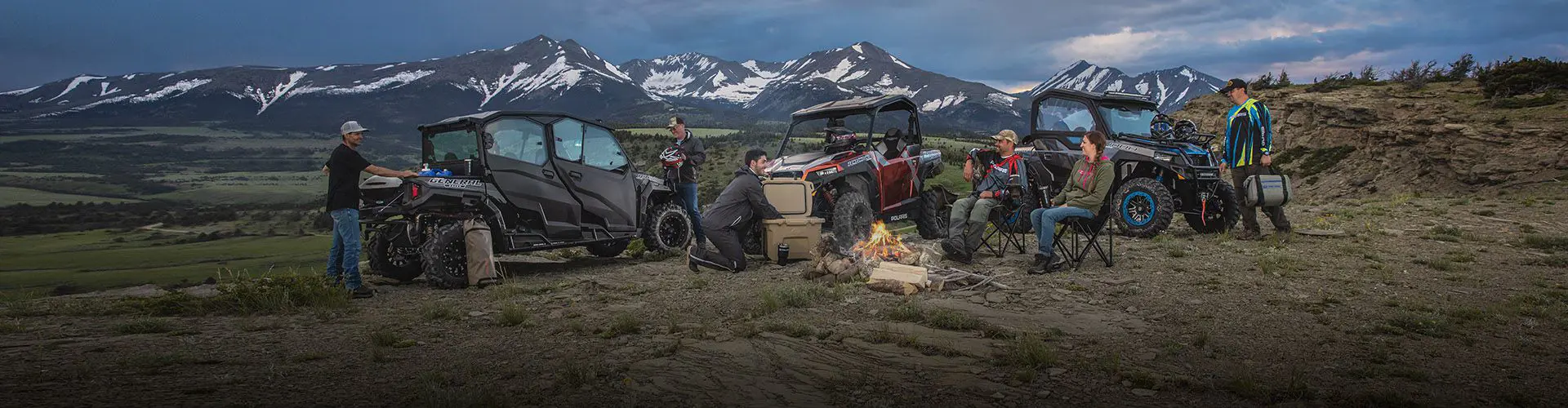 Campers with UTVs around a campfire