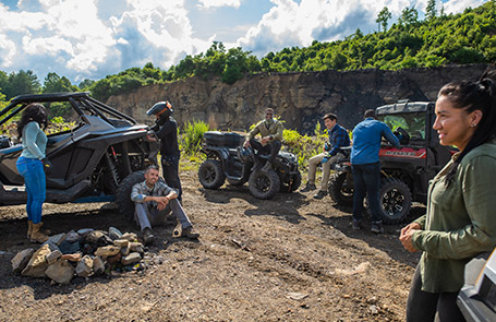 A group of friends enjoying a time in nature next to their Polaris Off-Road vehicles