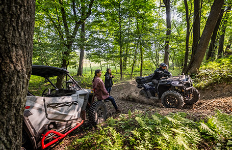 Three Polaris Off-Road riders using their vehicles in the forest
