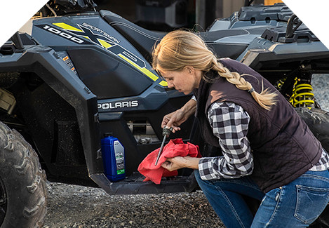 Mujer revisando el aceite de un Polaris Sportsman