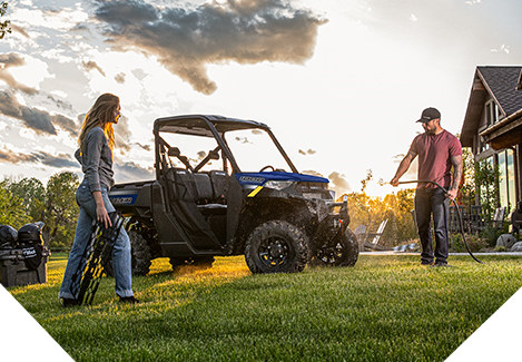 Hombre y mujer limpiando un Polaris Ranger en el campo