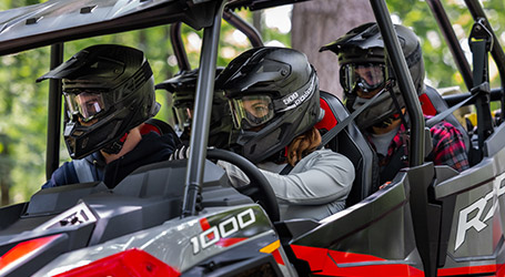 Four people wearing their Polaris Riding Gear inside their RZR