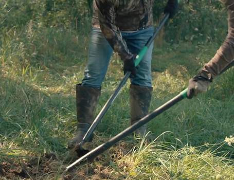 dos personas trabajando en la tierra con herramientas