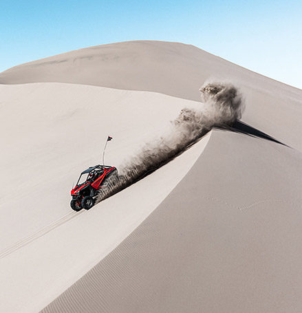 A RZR driven down a dune