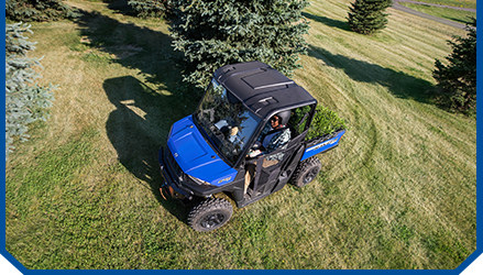 A person driving a blue Ranger on the lawn