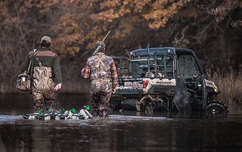 Two hunters walking in the water to their Ranger vehicle