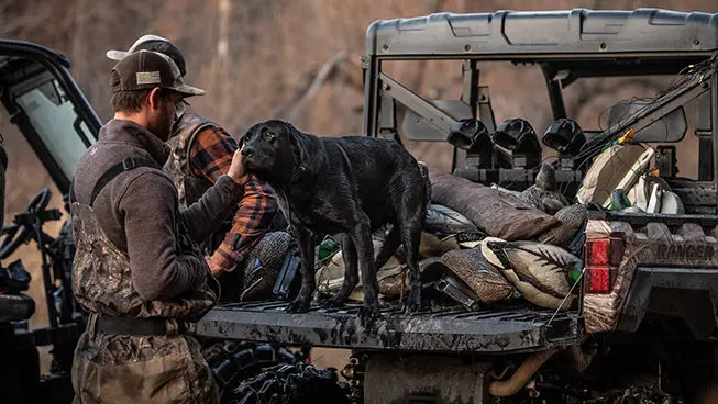 A hunter and his dog on a Ranger vehicle