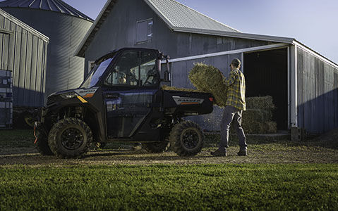 A man loading hay in the back of a Ranger 1000